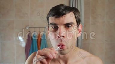 年轻迷人的男人刷牙照镜子。 他用<strong>牙刷</strong>刷牙。 对<strong>儿童</strong>的照料